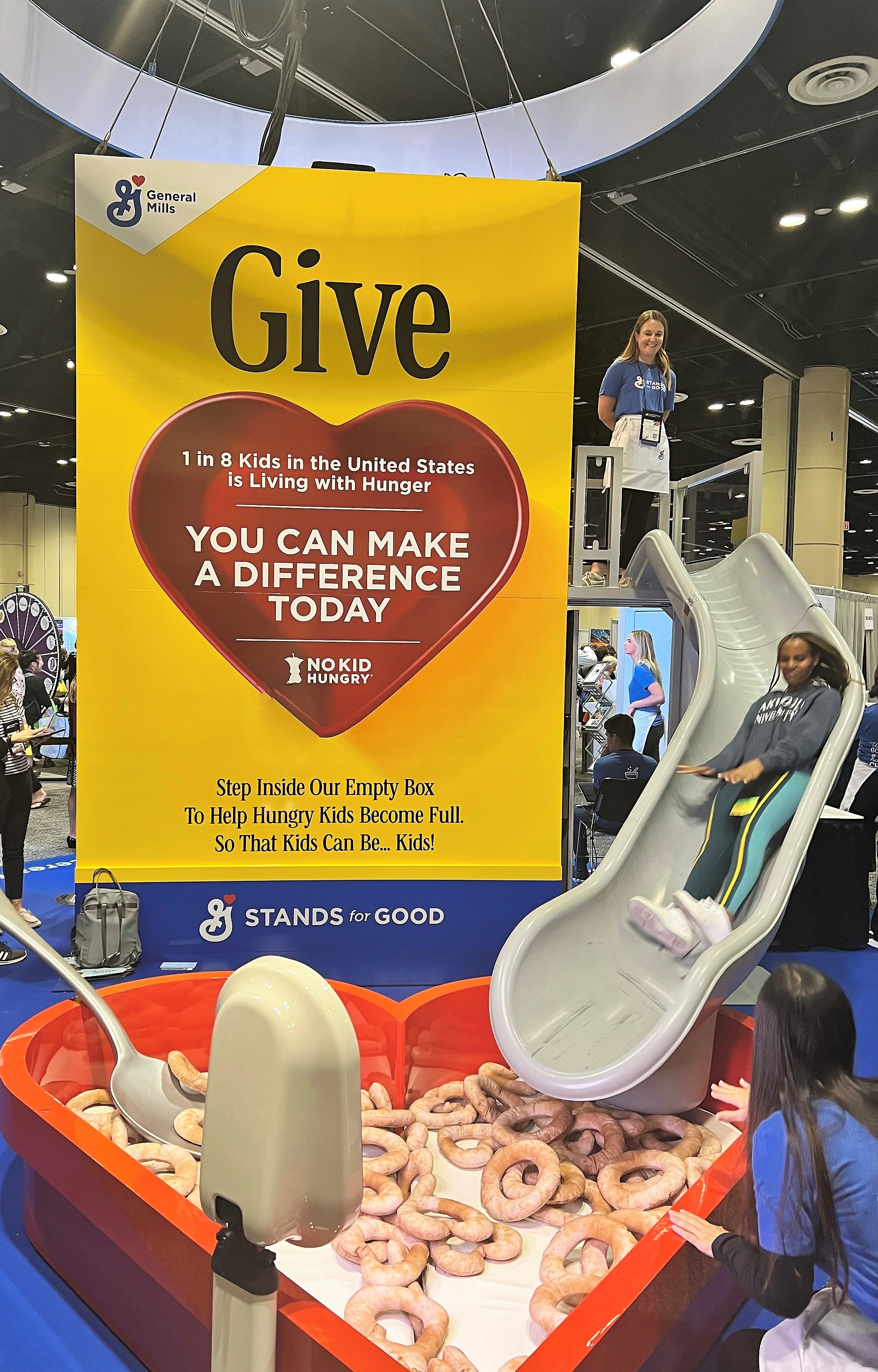 Woman sliding down giant slide at General Mills booth at FNCE