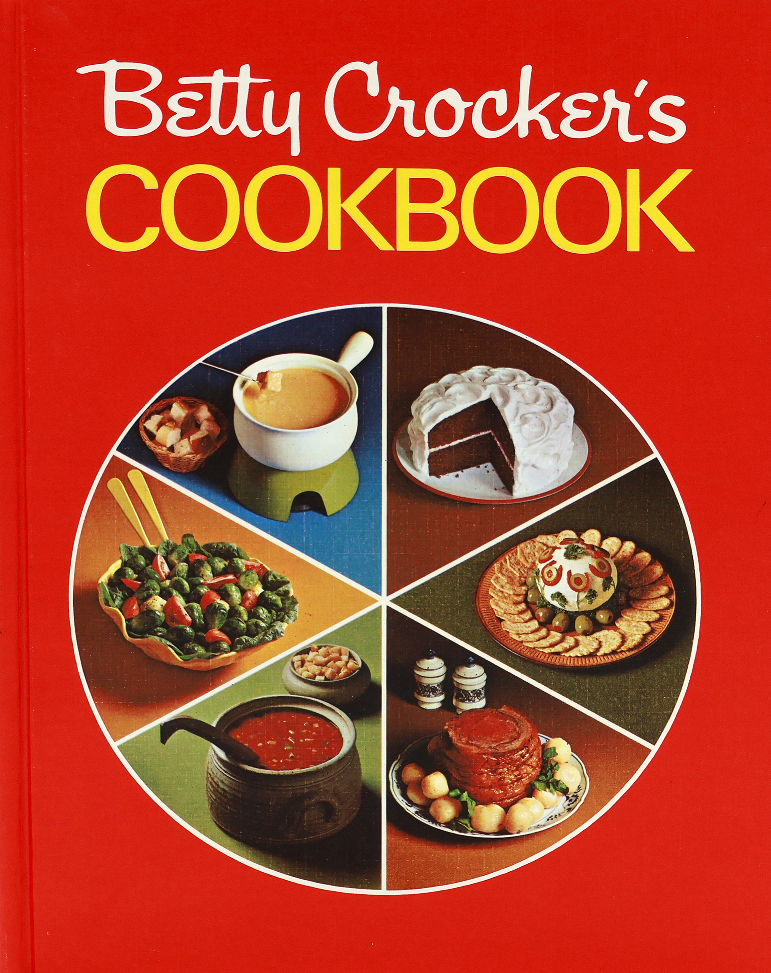 Cover of the 1969 Betty Crocker Cookbook with a red cover that has a circle on it cut into wedges like a pie.  The 6 wedges contain: fondue pot; chocolate cake, cheeseball with crackers, rib roast surrounded by small whole potatoes, soup, and a salad with brussels sprouts and tomato wedges.